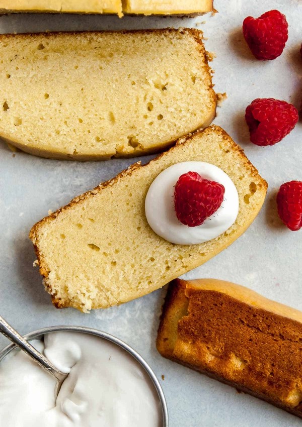 slices of pound cake with raspberries and coconut whipped cream on a spoon
