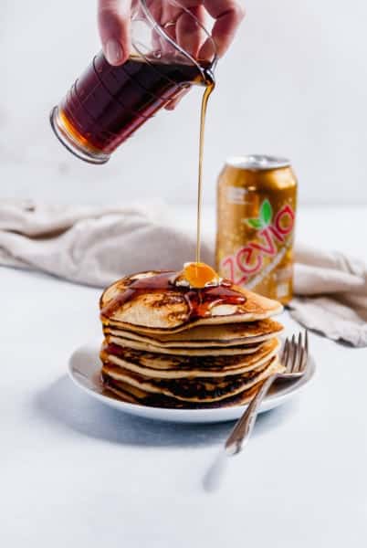 pancakes on a plate with syrup being poured onto them